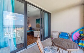 A balcony with a sliding glass door, a wooden chair, a small table, and a surfboard. - Seconds from Sand & Stunning Sea Views (St Thomas)
