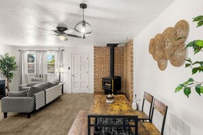 A modern living room with a fireplace, grey sofa, dining table, and a ceiling fan. - Charming 2 bedroom retreat at the end of the street equipped for any length stay (Las Cruces)