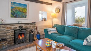 Un salon chaleureux avec une cheminée, un canapé de couleur turquoise et une table sur laquelle sont posées des tasses et une théière.