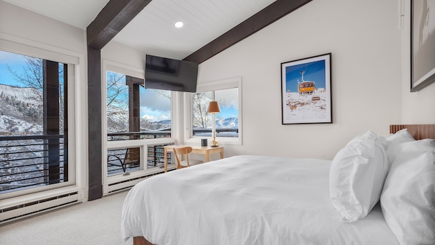 A bedroom with a large bed, a desk, and a window overlooking a snowy landscape. - Enclave 313 | Ski-In/Ski-Out Condo w/Shared Pool/Hot Tub/Gym/WiFi (Snowmass Village)