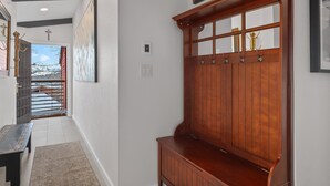 A hallway with a wooden bench, a door leading outside, and a wall-mounted light switch. - Enclave 313 | Ski-In/Ski-Out Condo w/Shared Pool/Hot Tub/Gym/WiFi (Snowmass Village)