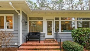 A house with a covered porch, a bench, and a small garden area. - Barrett Tee House - Stunning Home in the Village! (Pinehurst)