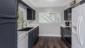 A modern kitchen with dark cabinetry, a stainless steel sink, and a built-in oven. - Family & Pet Friendly Beach Getaway (Clearwater)