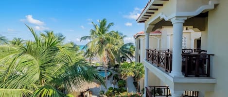 A resort with a pool, palm trees, and a balcony with outdoor furniture.