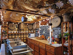 A restaurant interior with a wooden ceiling, hanging lights, a chalkboard menu, and buffet counters.