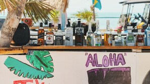A bar with various bottles of alcohol and a sign with the word "ALOHA". - 1BR/1BTH Sea View Suite | Cobia 503 | La Beliza (San Pedro)