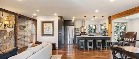 A modern kitchen with a central island, bar stools, and a dining area with a wooden table and chairs.