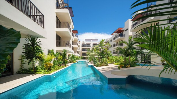 A swimming pool with a view of multi-story buildings, surrounded by tropical plants. - Depa Moderno con Alberca Tulum 1 Rec (Tulum)