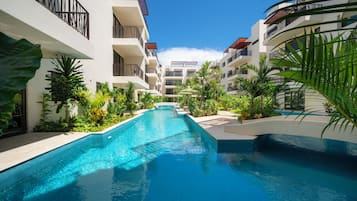 Alberca al aire libre, sombrillas en la alberca y camastros