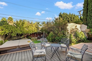 Eine Terrasse im Freien mit Holzboden, Metallstühlen und einem kleinen Tisch.