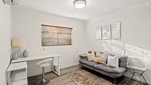 Un salon moderne avec un canapé gris, un bureau blanc et un tapis en fourrure.