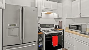 Une cuisine compacte équipée d’un réfrigérateur en acier inoxydable, d’une cuisinière à gaz et d’un four à micro-ondes.