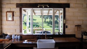 A kitchen with a large window, wooden counter, and a sink.