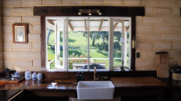 A kitchen with a large window, wooden counter, and a sink.