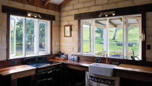 A kitchen with a stove, oven, sink, and large windows offering views of a grassy landscape.