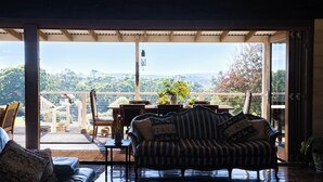 A cozy seating area with a sofa and chairs, a dining table, and a view of a lush landscape.