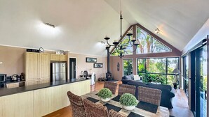 Une cuisine moderne avec un coin repas, des meubles en bois, un plan de travail noir et une grande fenêtre qui laisse entrer la lumière naturelle.