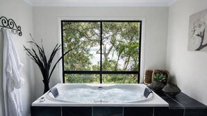 Une salle de bain moderne avec une grande fenêtre, une baignoire et une plante en pot.
