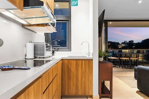 Una cocina moderna con armarios de madera, horno integrado y ventana con vistas a un balcón.