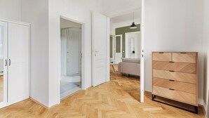 Käytävä, jossa on kalanruotokuviollinen puulattia, valkoiset seinät ja puinen kaappi laatikoineen.