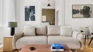 Moderni olohuone, jossa on beige sohva, kirja pöydällä ja lattiavalaisin.