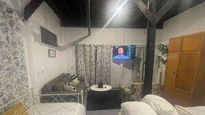 Habitación de hotel con dos camas, una mesita, un televisor y un armario.