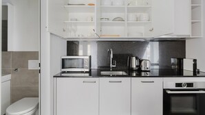 A modern kitchen with white cabinets, a black countertop, a microwave, a toaster, a kettle, and a dishwasher. - Blueground | Sihlfeld, washer/dryer, nr Zürich HB (Zurich)
