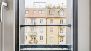 A view through a window of a multi-story building with balconies and a metal railing. - Blueground | Sihlfeld, washer/dryer, nr Zürich HB (Zurich)