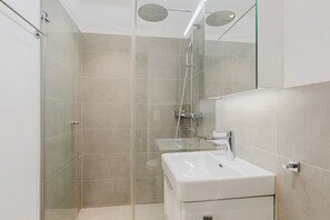 A modern bathroom with a glass-enclosed shower, a white sink, and a mirror above the sink. - Blueground | Sihlfeld, washer/dryer, nr Zürich HB (Zurich)