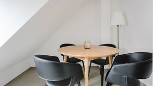 A round table with a vase, four black chairs, and a floor lamp in a room with white walls and a sloped ceiling. - Blueground | Sihlfeld, washer/dryer, nr Zürich HB (Zurich)