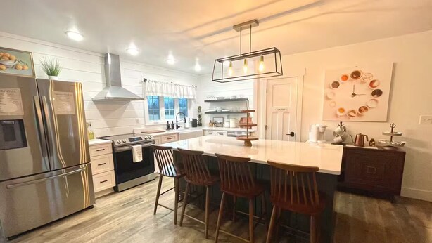 A modern kitchen with a central island, stainless steel appliances, and a hanging light fixture.