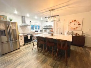 A modern kitchen with a central island, stainless steel appliances, and a hanging light fixture.