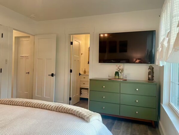 A bedroom with a bed, a green dresser, a television, and a door labeled "PONDER ROOM".