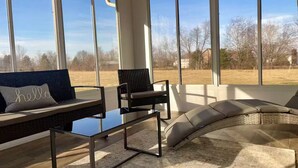A sunlit room with a large window, a sofa, a chair, and a coffee table.