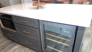 A kitchen with a white countertop, grey cabinets, and a built-in oven.