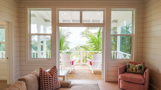 Een kamer met een houten terras, een bank, een stoel en uitzicht op de oceaan.