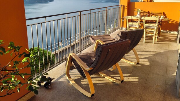 A balcony with two chairs, a table, and a view of a lake and mountains. - Romantic house. Veranda with panoramic view. Garden. Barbecue. Parking space (Colonno)