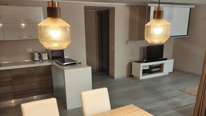A modern kitchen with white cabinets, a microwave, and a coffee maker. There is a dining area with a wooden table and chairs. - Romantic house. Veranda with panoramic view. Garden. Barbecue. Parking space (Colonno)