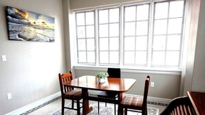 Un comedor con una mesa y sillas de madera, un tapete y una ventana con persianas.