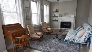 Una sala de estar con un piano, dos sillones, un sofá, una chimenea y un televisor.