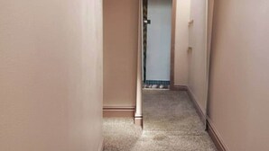 En smal hall med mattbeklädd golv och beige väggar.