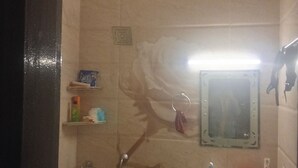A bathroom with a shower, a sink, a mirror, and a ceiling fan. - Loginn Stays #1 (Gurugram)