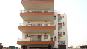 A multi-story residential building with balconies, air conditioning units, and a gated entrance. - Loginn Stays #1 (Gurugram)