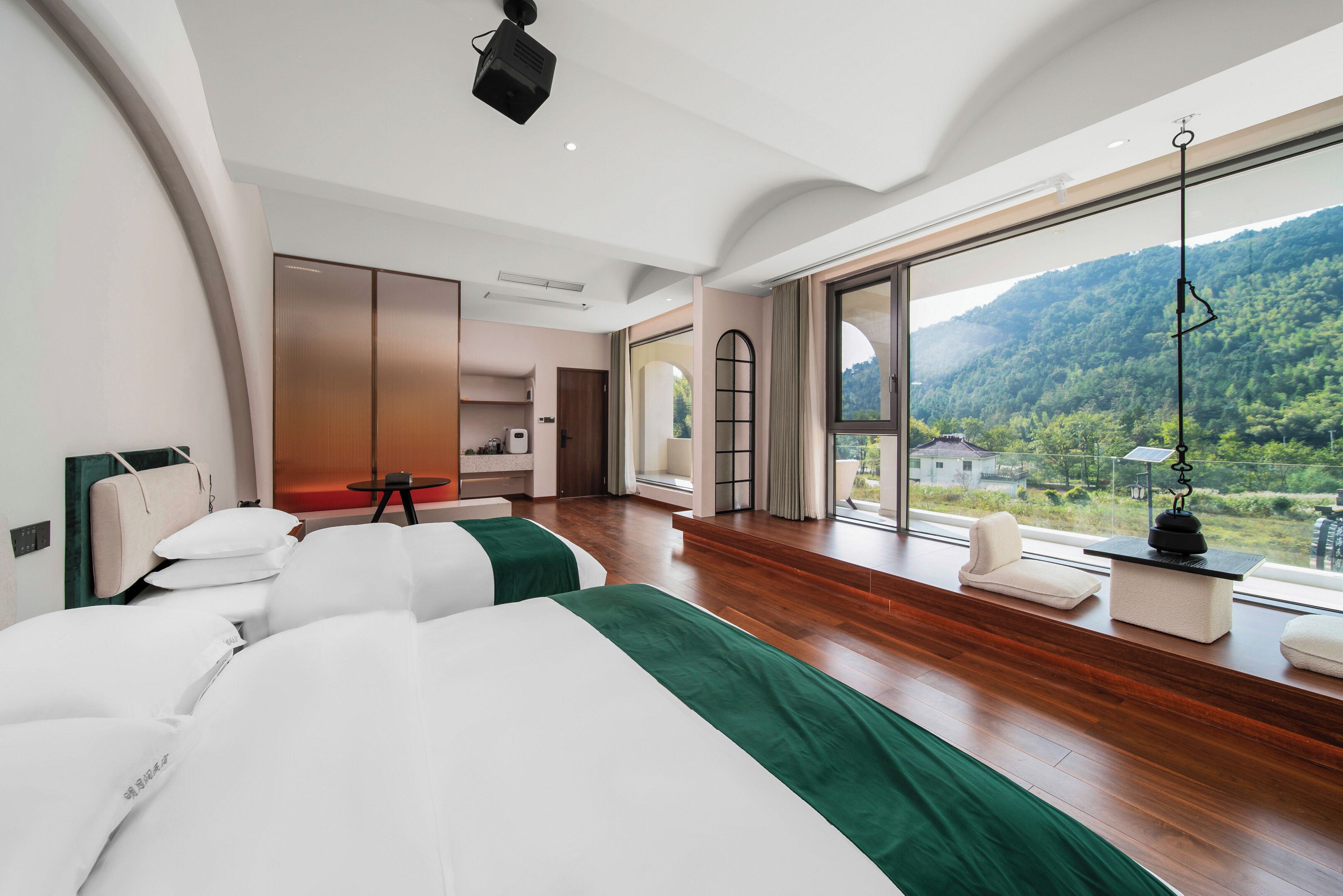 Una habitación de hotel moderna con dos camas, un ventanal grande y vistas a un paisaje montañoso.