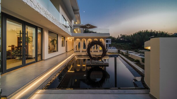 A modern house with a reflective pool, large windows, and a well-lit outdoor area. - Bright Moon Valley Smart Hotel (Anqing)