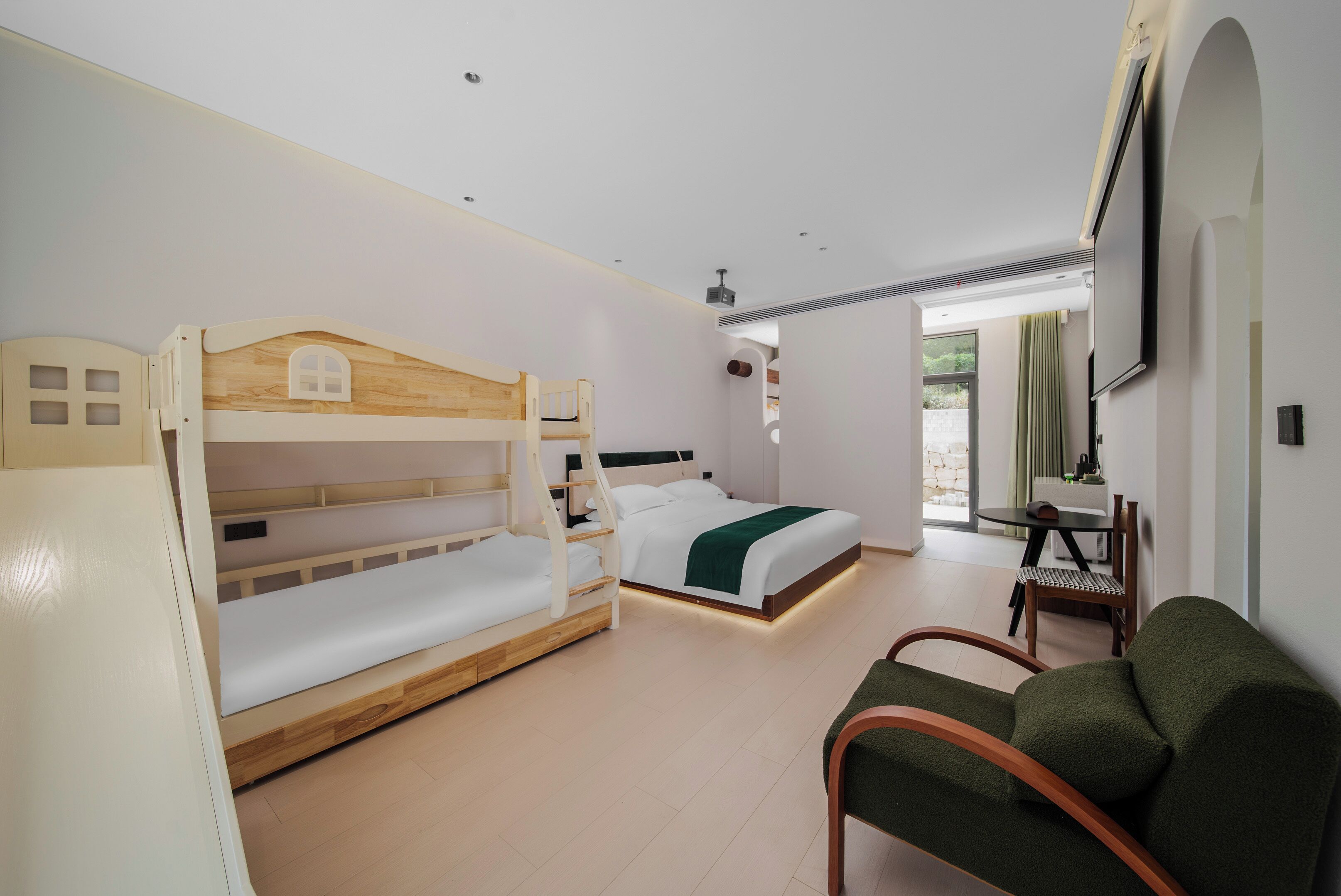 Une chambre d’hôtel avec des lits superposés, un canapé, une télévision et une vue sur l’extérieur.