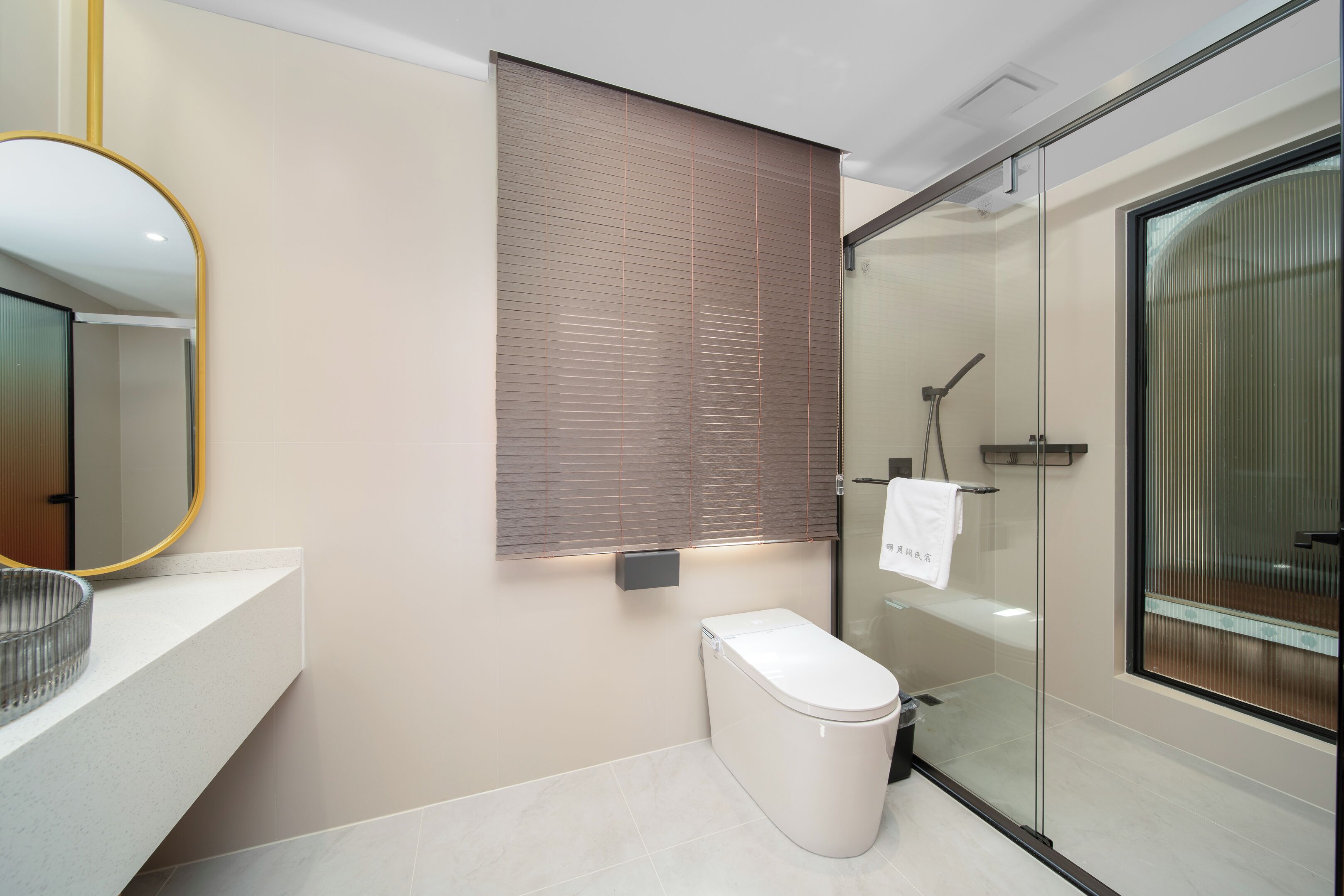 A modern bathroom with a toilet, a glass shower enclosure, and a mirror with a gold frame.