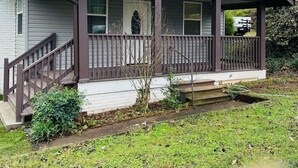 A single-story house with a front porch, a small front yard, and a visible garage door. - Cozy and comfortable accommodation for six guests. (Dalton)
