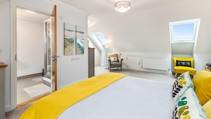 Une chambre à coucher avec un lit, une chaise, un fauteuil jaune, un puits de lumière et un radiateur.