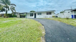 A single-story house with a front porch, a garage, and a small lawn. - Modern King Suite Cozy Sofa Bed Near Everything (Pembroke Pines)